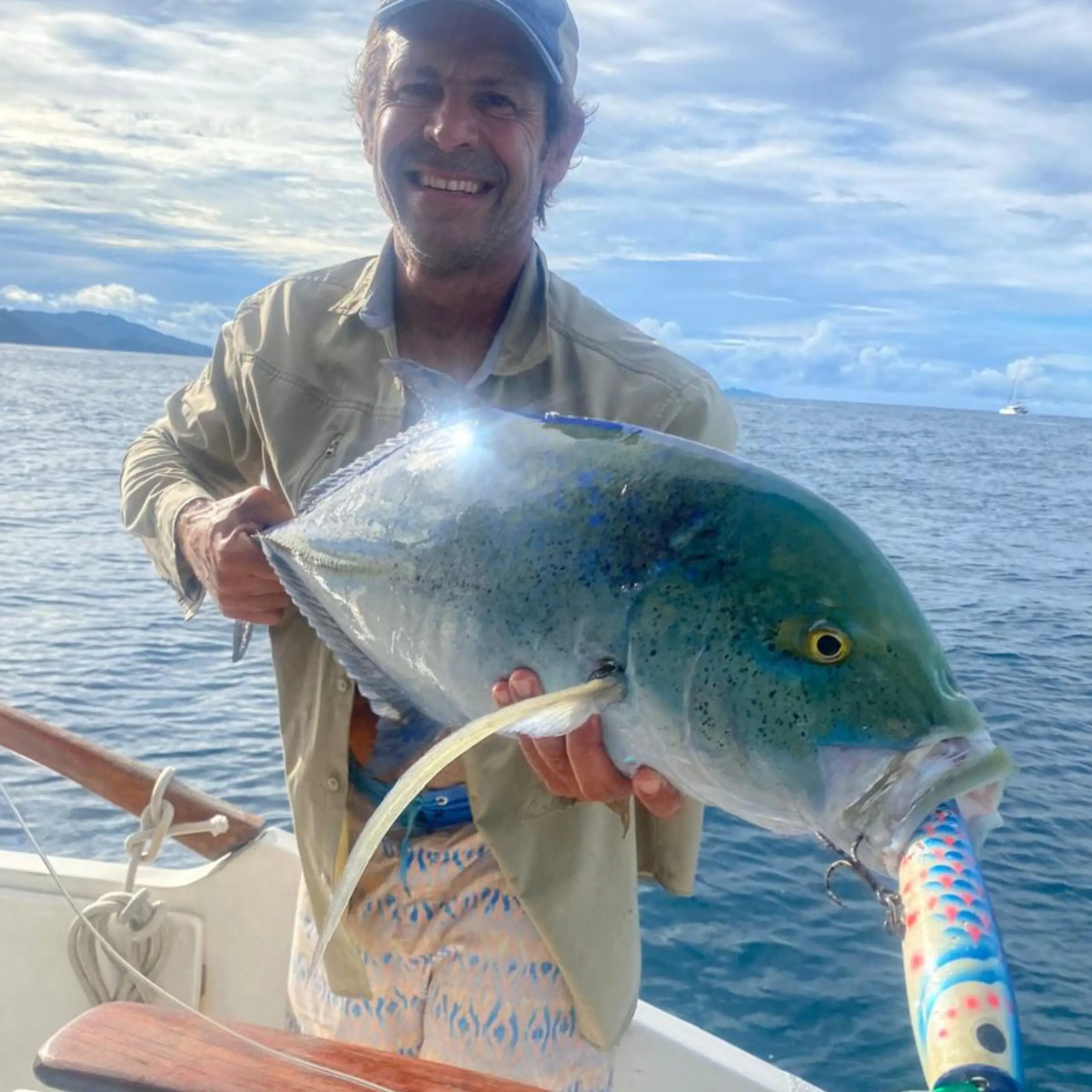 Fisherman holding a bluefin trevally in Seychelles waters prior to release